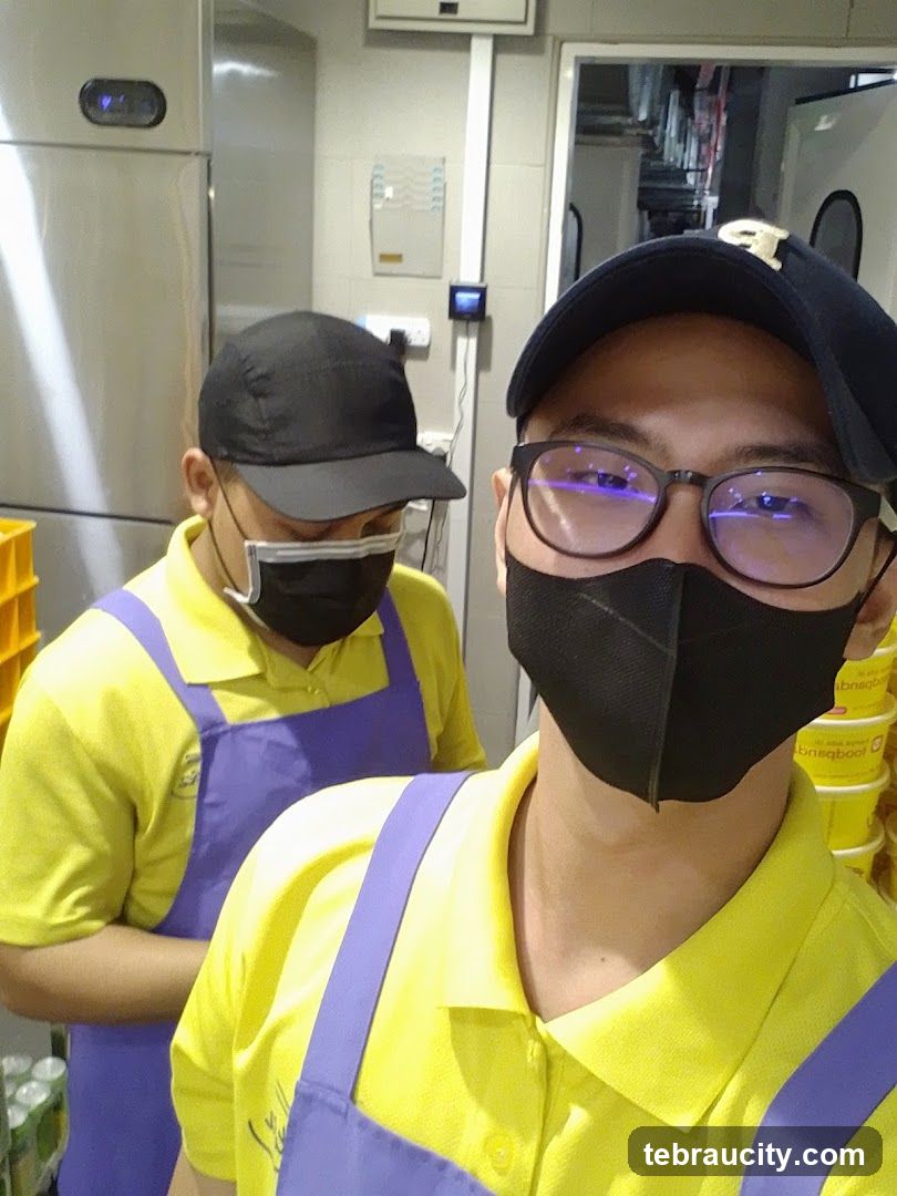 Two people in yellow shirts and purple aprons