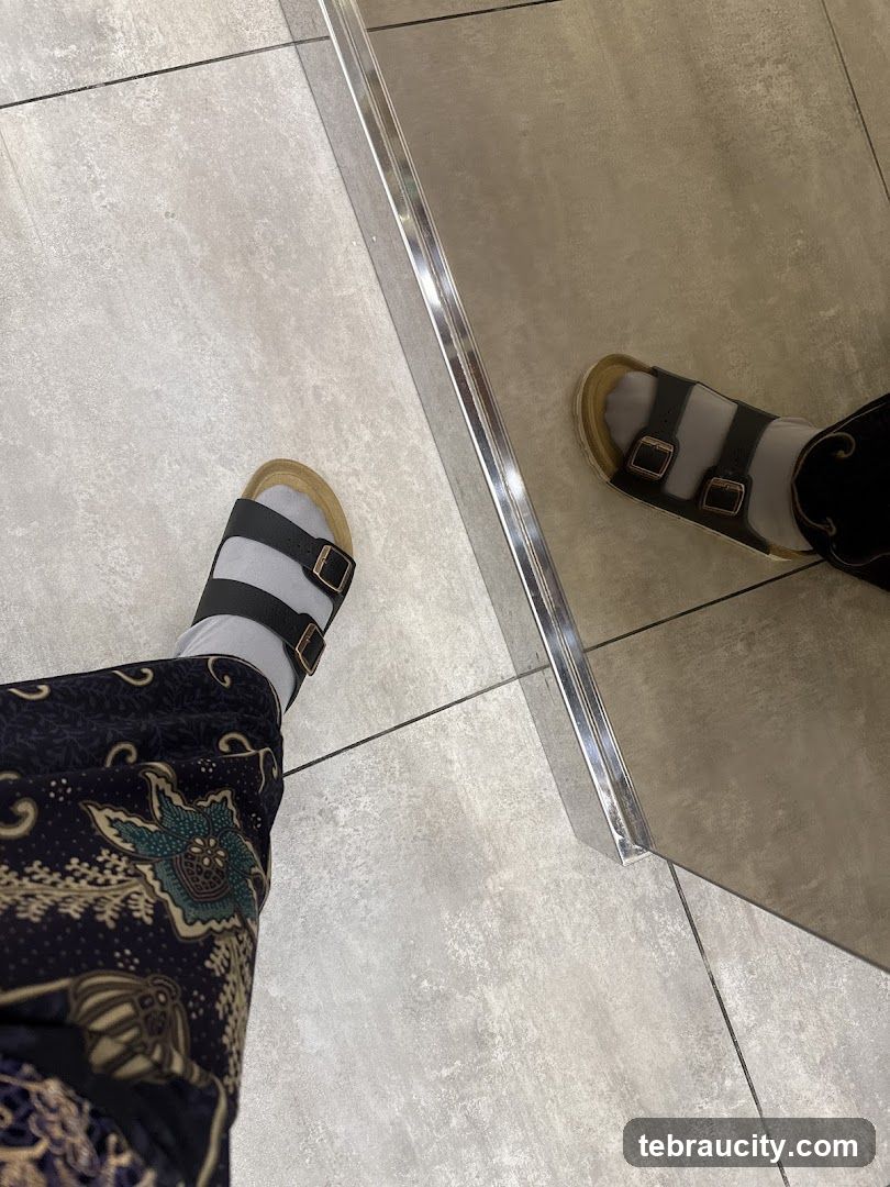 Feet in sandals and patterned pants reflected in a mirror