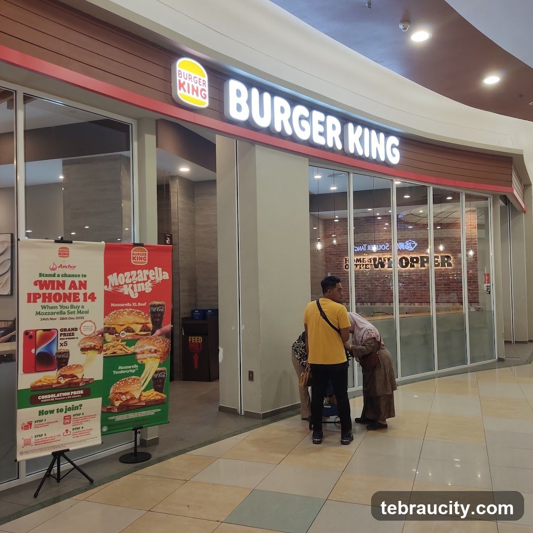 The exterior of a Burger King restaurant with its prominent signage. A promotional banner for a chance to win an iPhone 14 and a Mozzarella King meal is displayed outside the entrance.