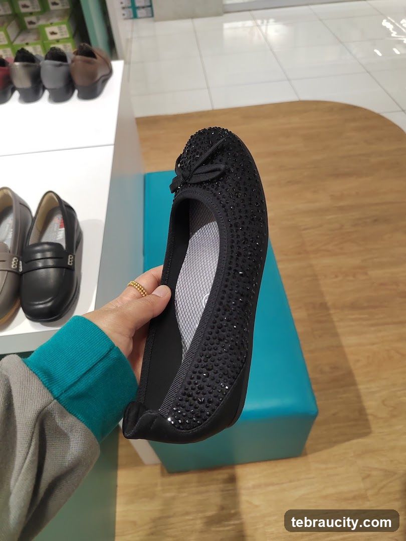 Woman holding a black embellished flat shoe