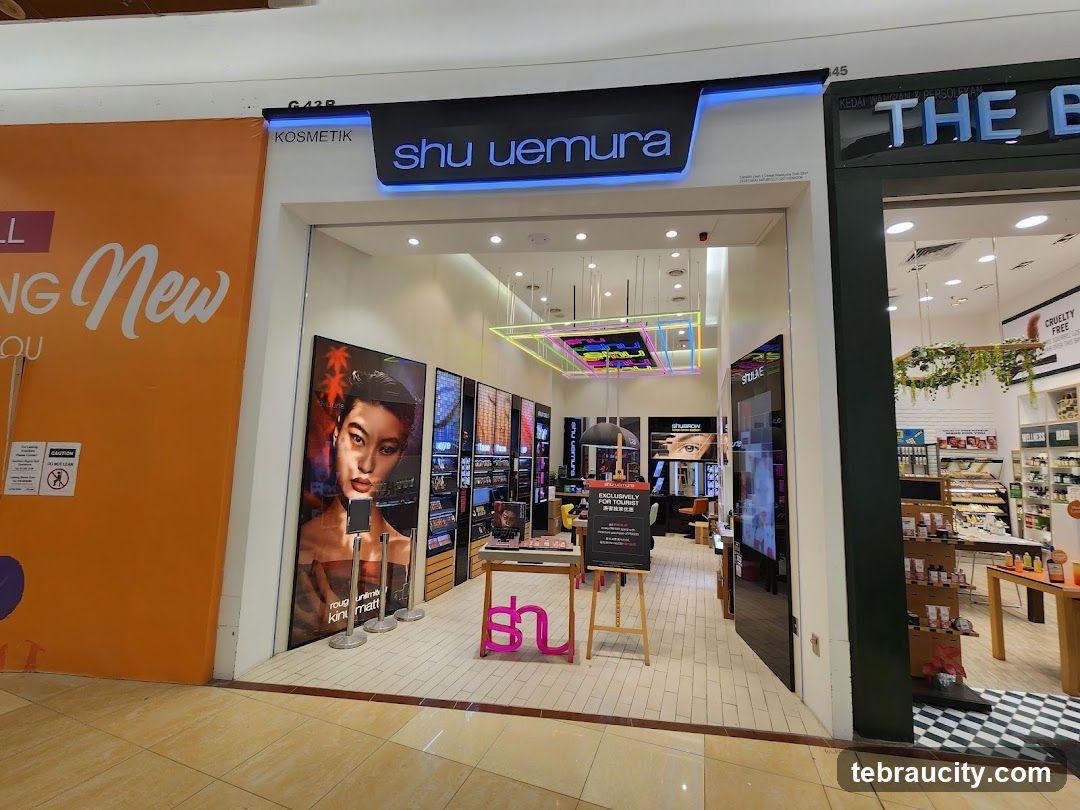 The exterior of a Shu Uemura cosmetics store. The store has a large display window with posters of models and makeup products. Inside, shelves are stocked with various beauty items.