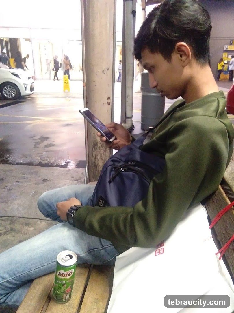 Man on bench with phone and drink
