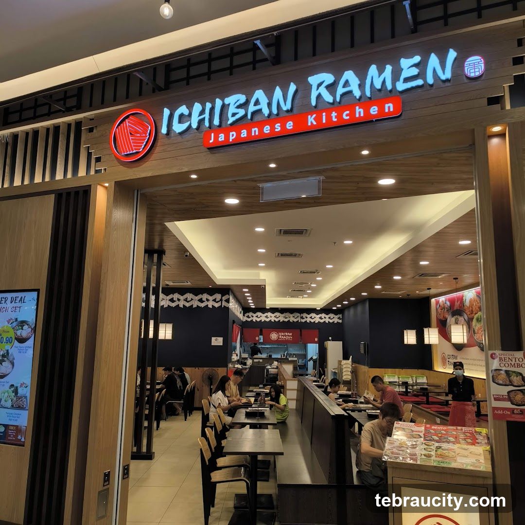 The exterior of Ichiban Ramen, a Japanese kitchen, with its prominent signage above the entrance. Inside, diners are seated at tables, and the restaurant appears to be well-lit with a modern interior design. A digital menu board is visible to the left, displaying a lunch set deal.