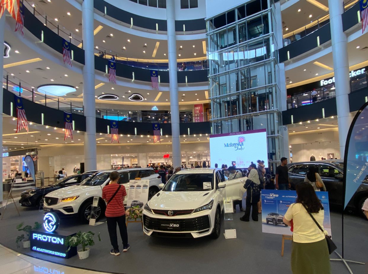 A sleek Proton car on display at a roadshow event.