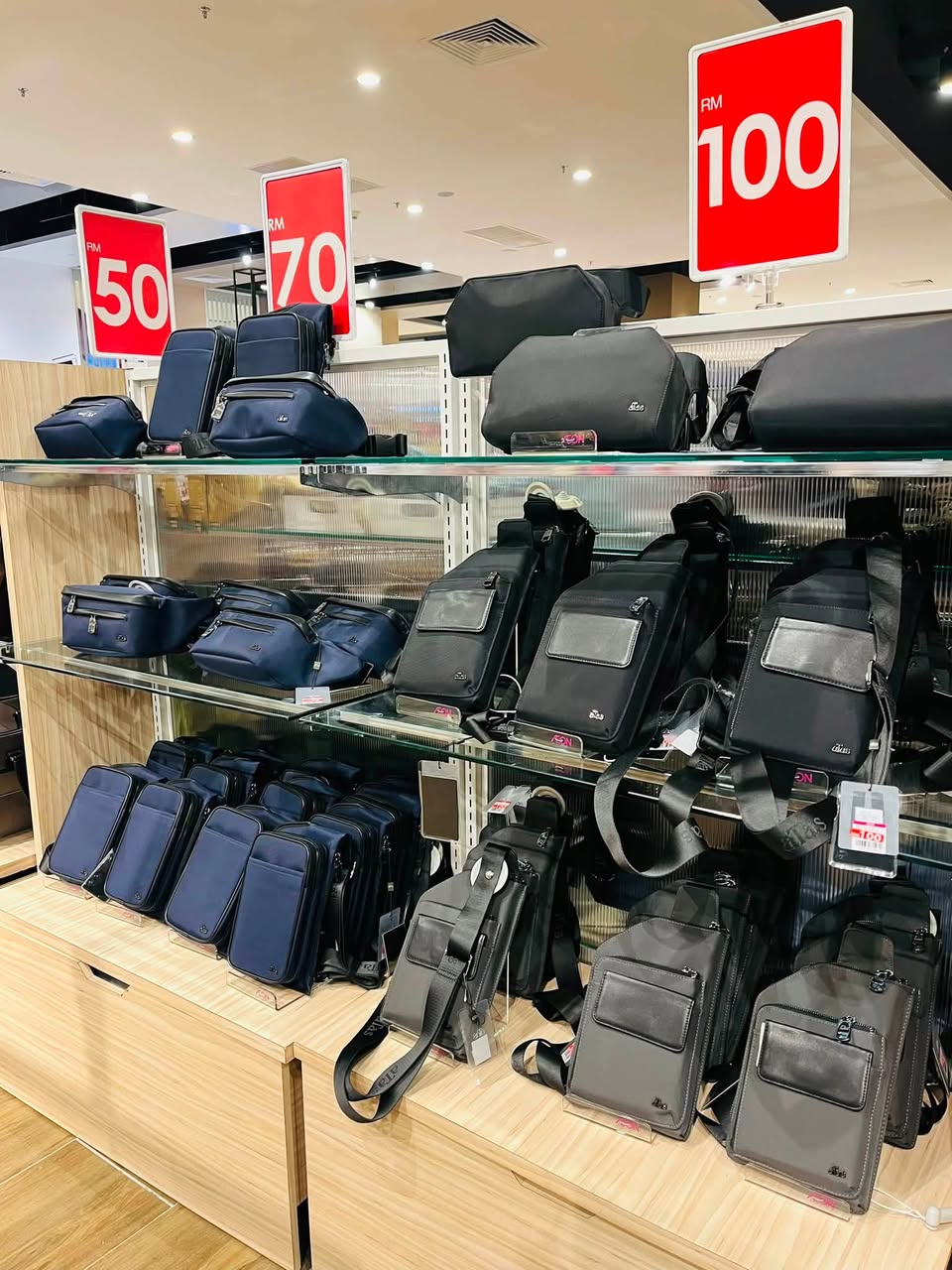 Men's leather satchels displayed across glass shelves