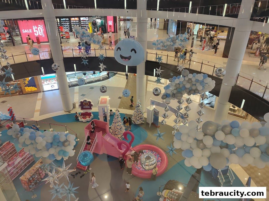 A festive mall interior with balloon decorations, a play area, and shops.