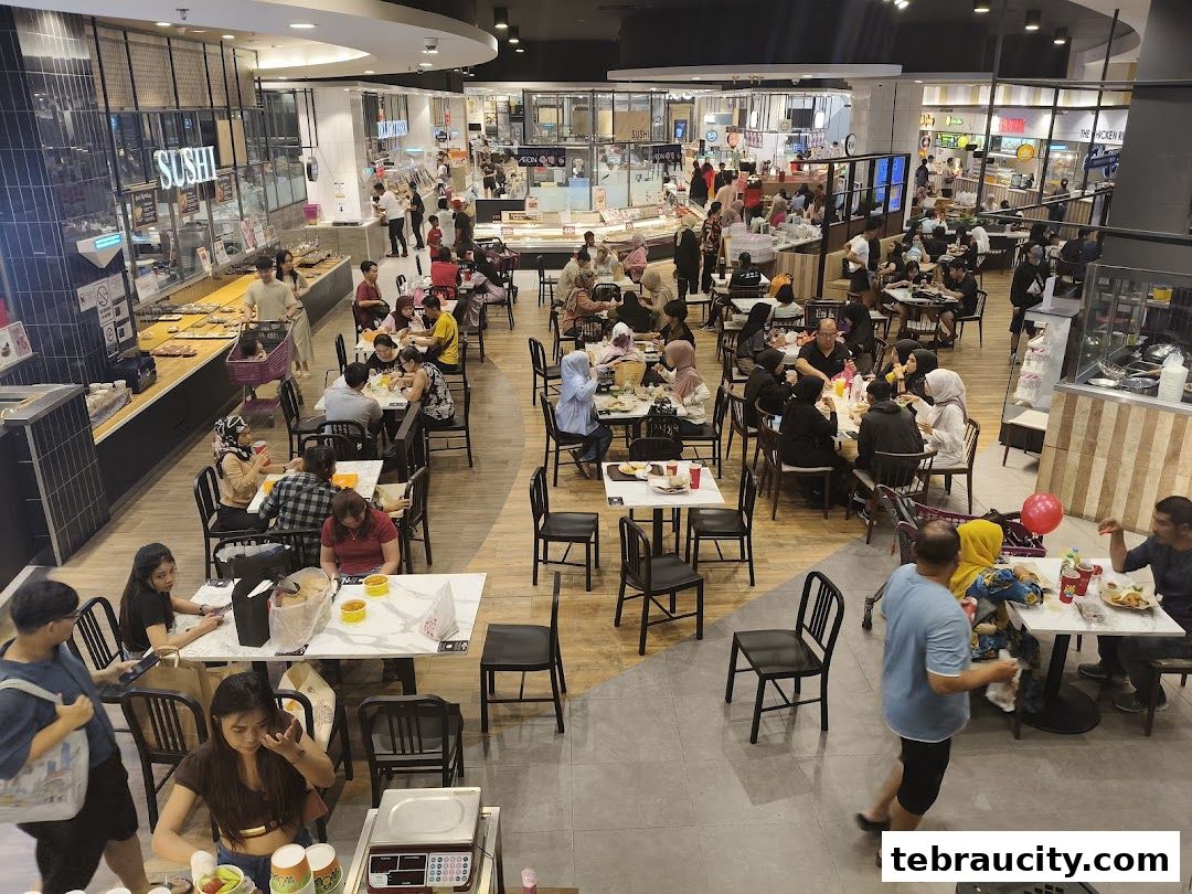 A busy food court with many people dining and queuing at various food stalls.