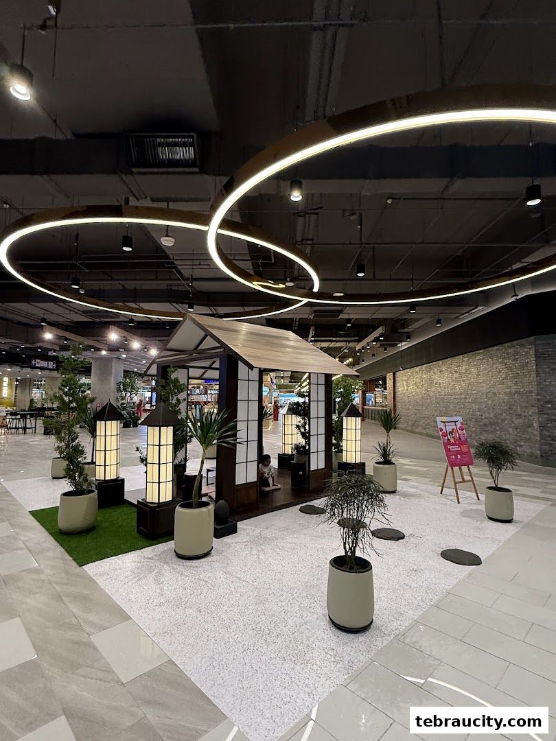 A Japanese-inspired display with a small house, plants, and decorative lighting in a mall.