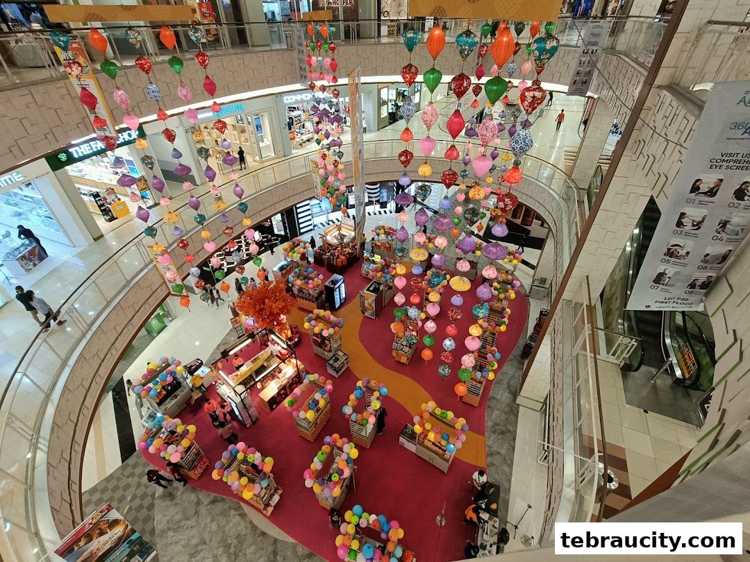 A high-angle view of a shopping mall atrium decorated with colorful lanterns and balloons.