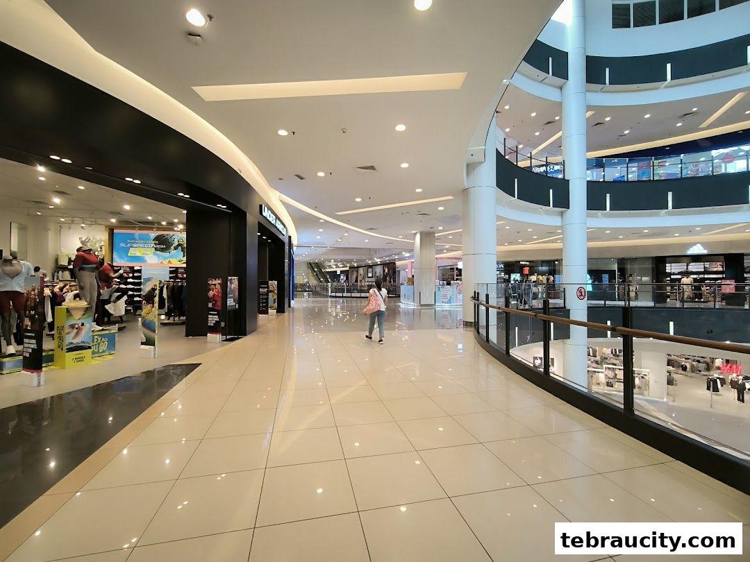Interior view of a modern shopping mall with various retail stores and escalators visible.