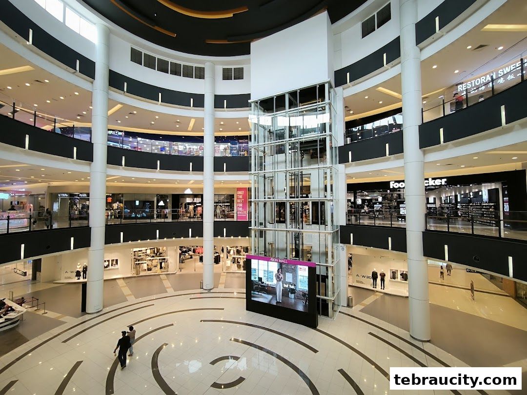Interior view of a multi-level shopping mall with escalators, shops, and a central atrium.
