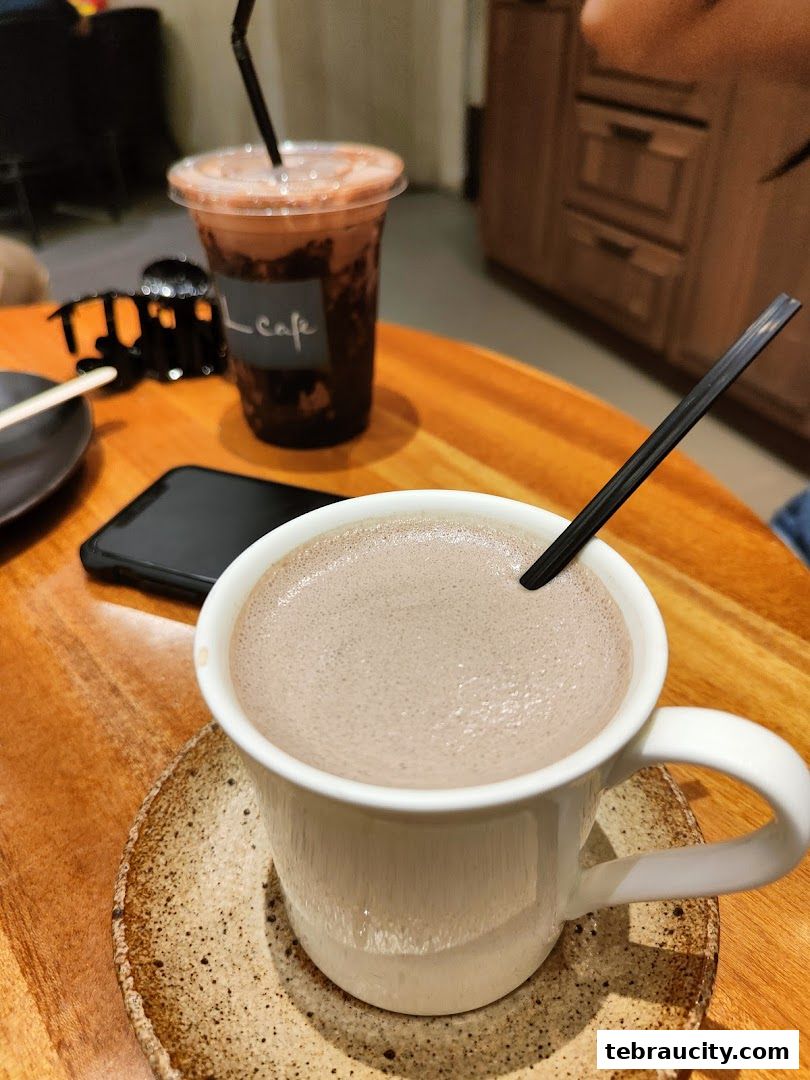 Two chocolate drinks, one in a mug and one in a to-go cup, on a wooden table.