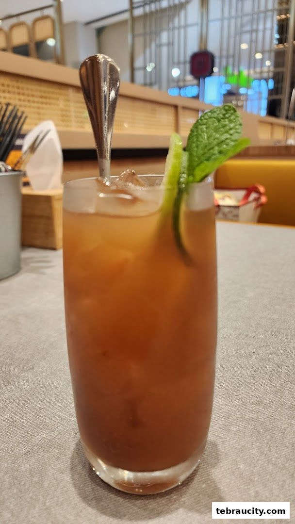A refreshing iced beverage with lime and mint garnish in a tall glass.