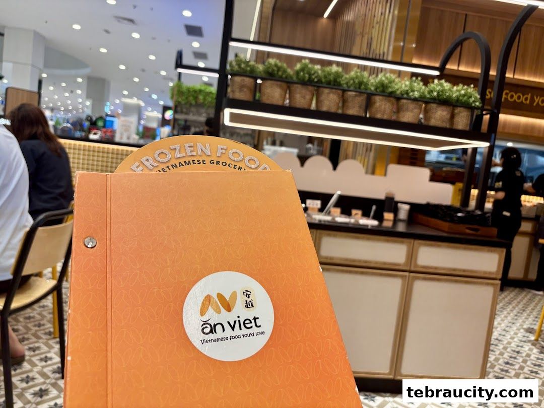 An orange menu from An Viet Vietnamese restaurant with a view of the restaurant interior.