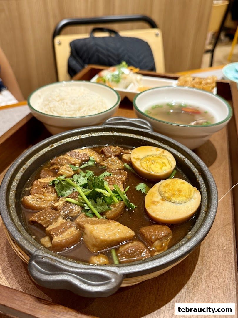 A close-up of a Vietnamese dish featuring braised pork belly with eggs, served with rice and soup.