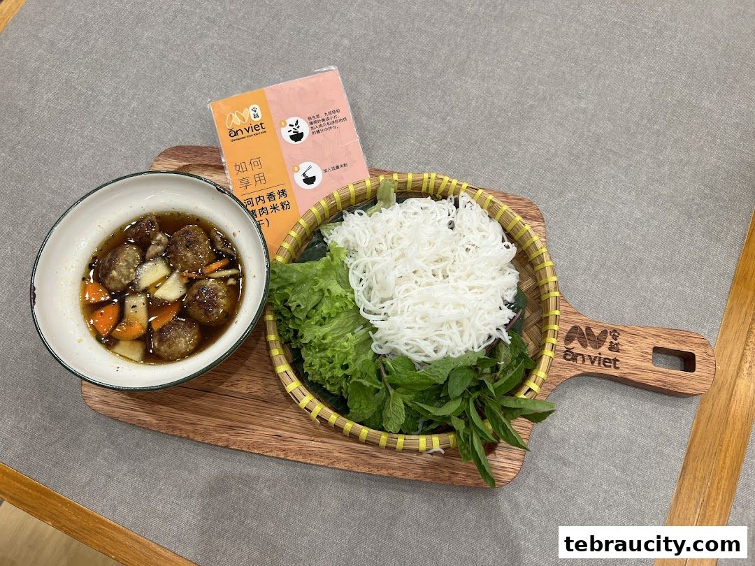 A Vietnamese dish featuring meatballs in broth, rice noodles, and fresh herbs on a wooden board.
