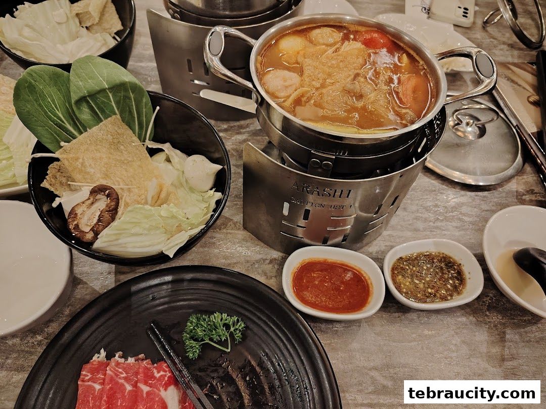 A table setting with a bubbling shabu-shabu pot, fresh ingredients, and dipping sauces.