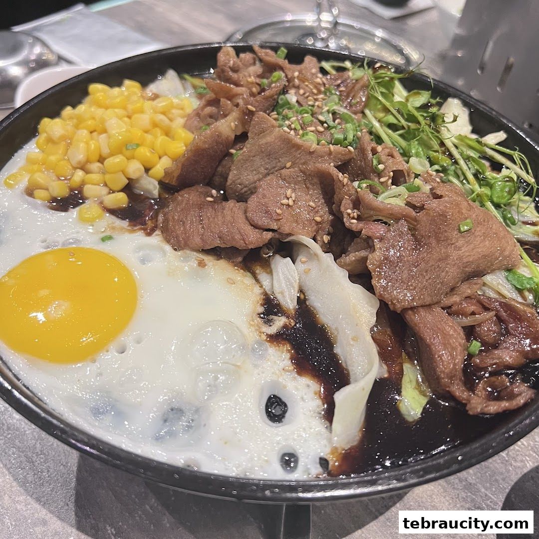 A sizzling hot plate dish with beef, corn, a fried egg, and greens.