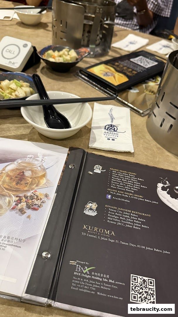 A table setting at Arashi Shabu-Shabu with menus, call button, and side dishes.