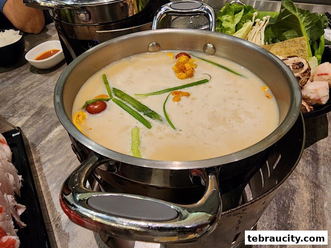 A steaming pot of creamy broth with vegetables and meat for shabu-shabu.