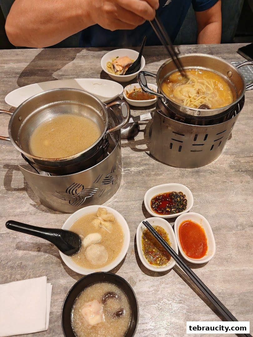 A table setting with shabu-shabu pots, dipping sauces, and bowls of food.