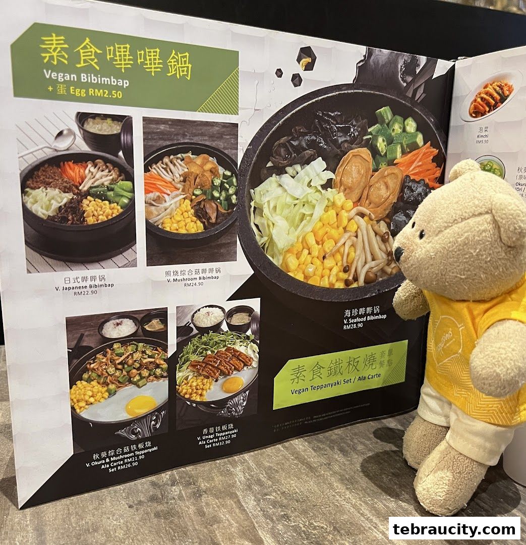 A teddy bear looks at a menu featuring various vegan bibimbap and teppanyaki dishes.