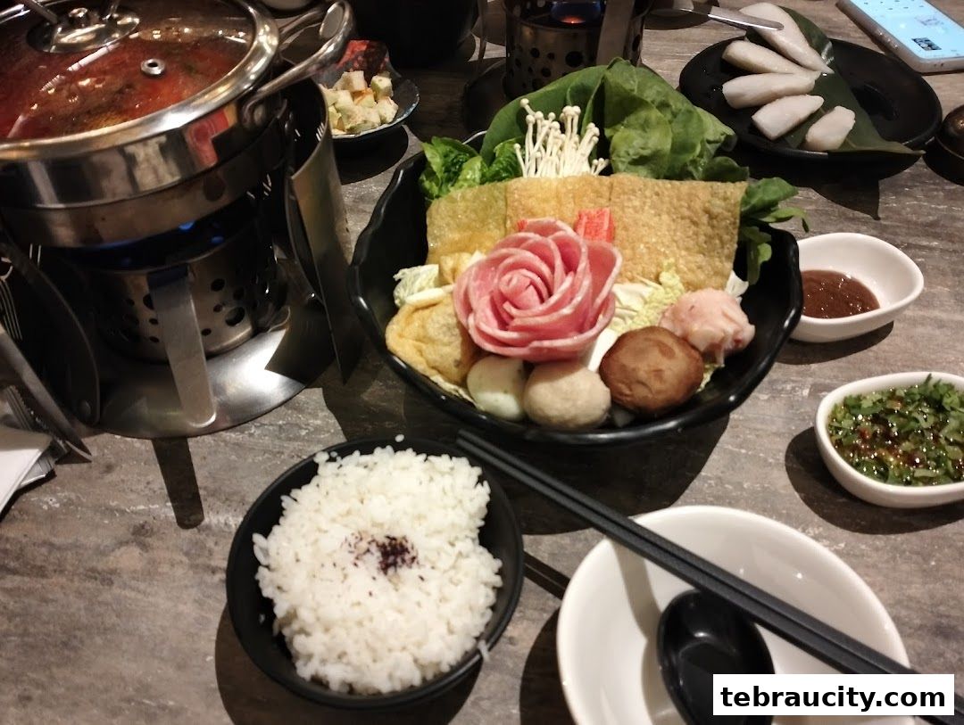 A table set for shabu-shabu with a pot, assorted ingredients, rice, and dipping sauces.