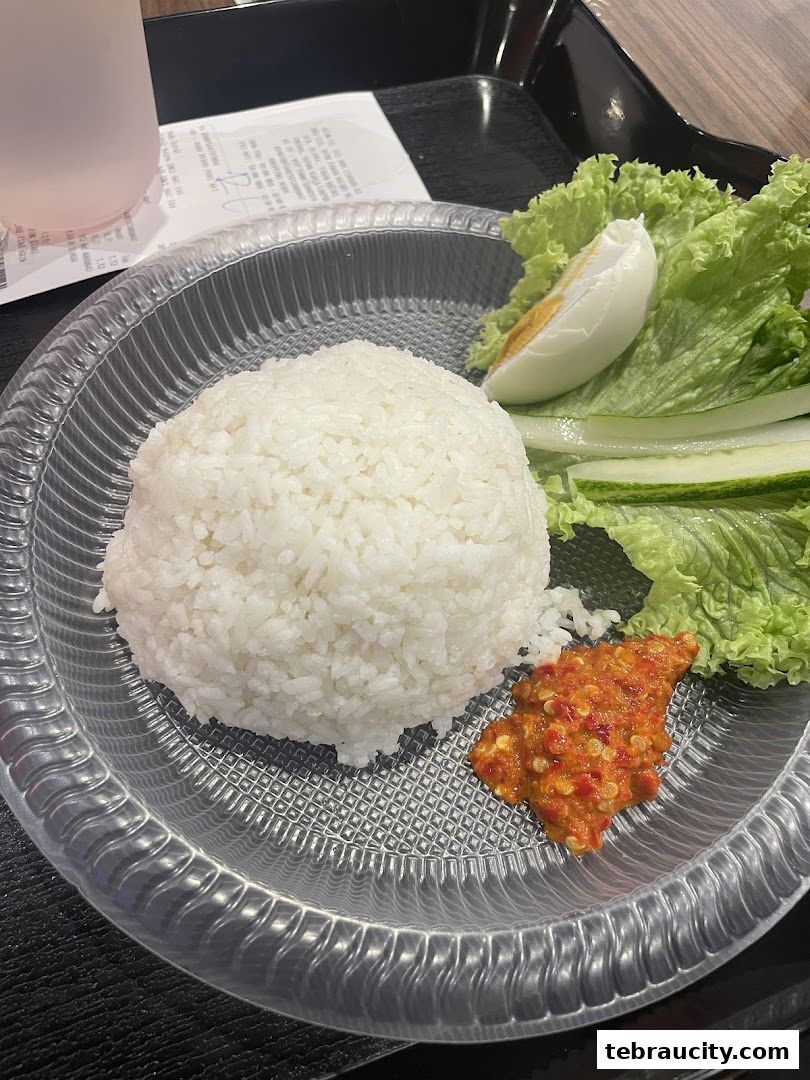 A plate of rice with salted egg, cucumber, lettuce, and sambal.