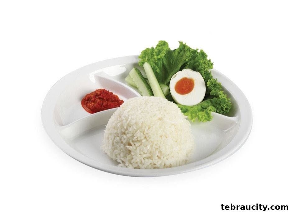 A plate of rice with chili paste, cucumber slices, lettuce, and half a salted egg.