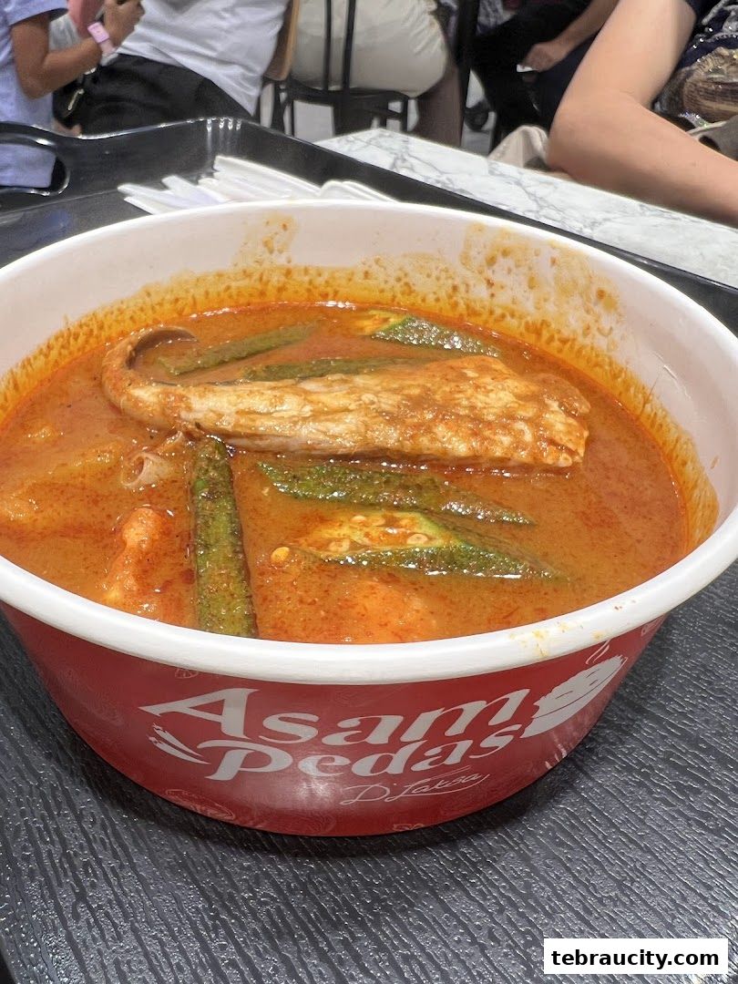 A close-up of a bowl of Asam Pedas fish with okra and curry.