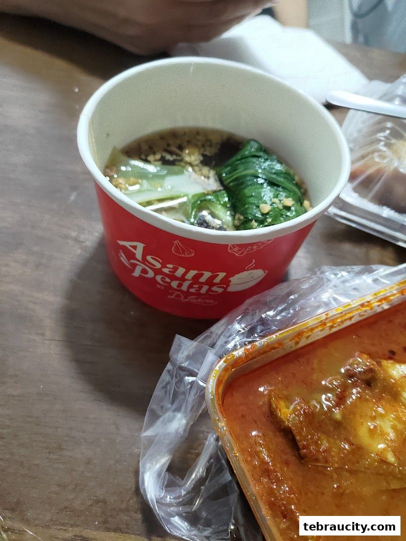 A close-up of two takeaway food containers, one with soup and vegetables, the other with curry.