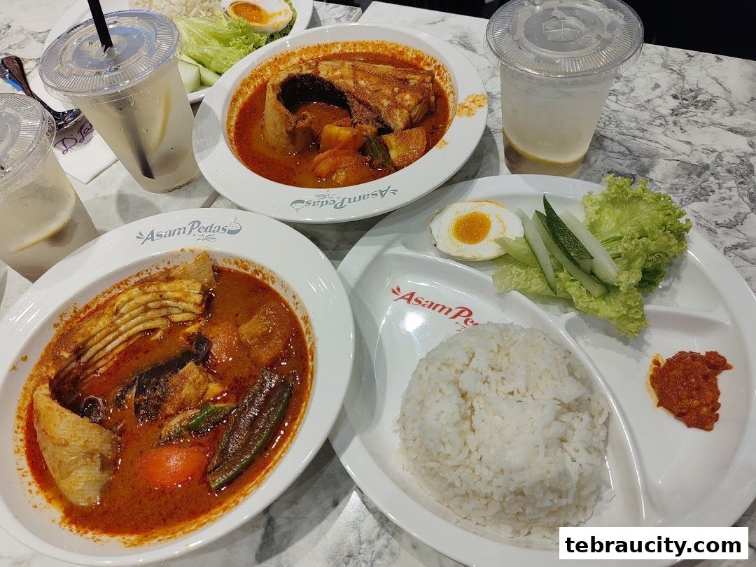 A spread of delicious Asam Pedas dishes with rice and refreshing drinks.
