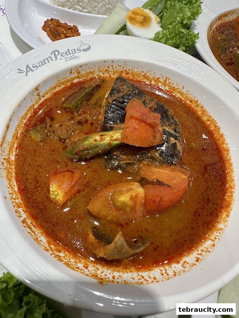 A close-up of a delicious Asam Pedas dish with fish, okra, and tomatoes.