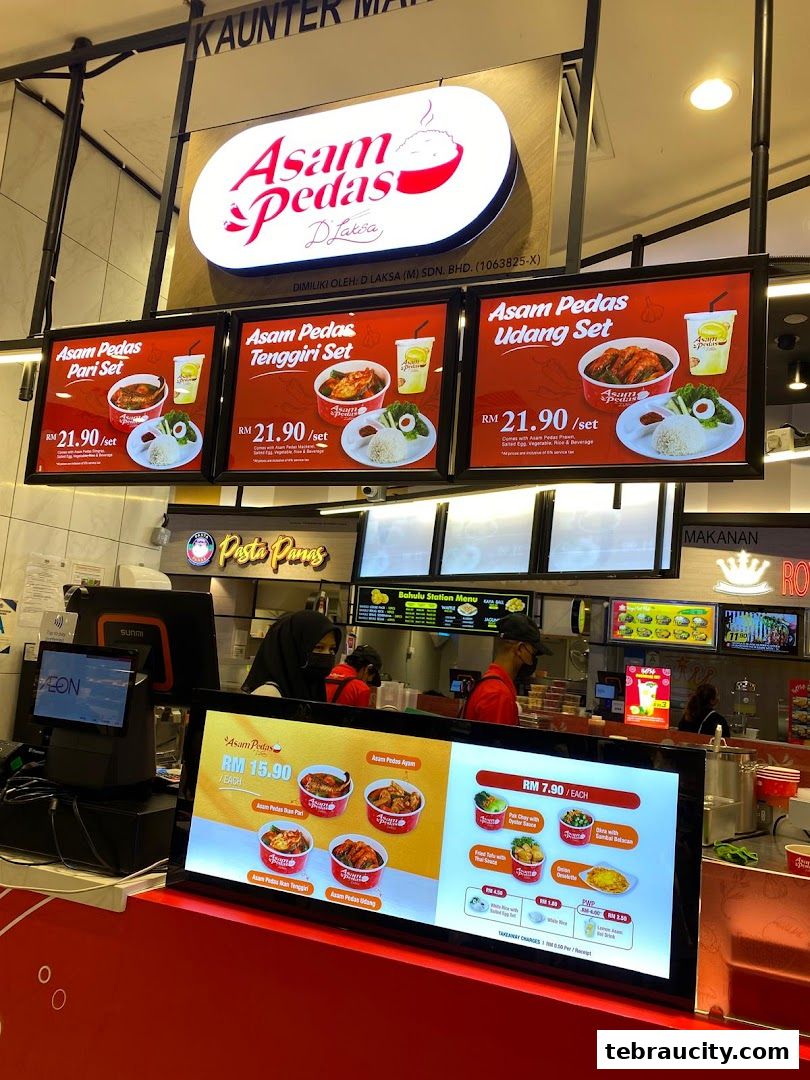 Digital menu boards displaying various Asam Pedas meal sets and individual dishes.