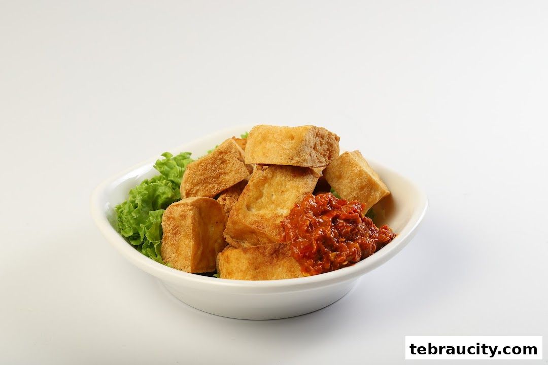 A white bowl filled with fried tofu pieces, lettuce, and a dollop of chili paste.