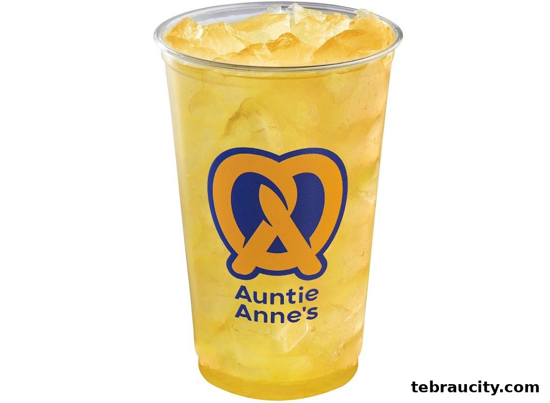 A tall plastic cup filled with ice and a yellow beverage, featuring the Auntie Anne's logo.