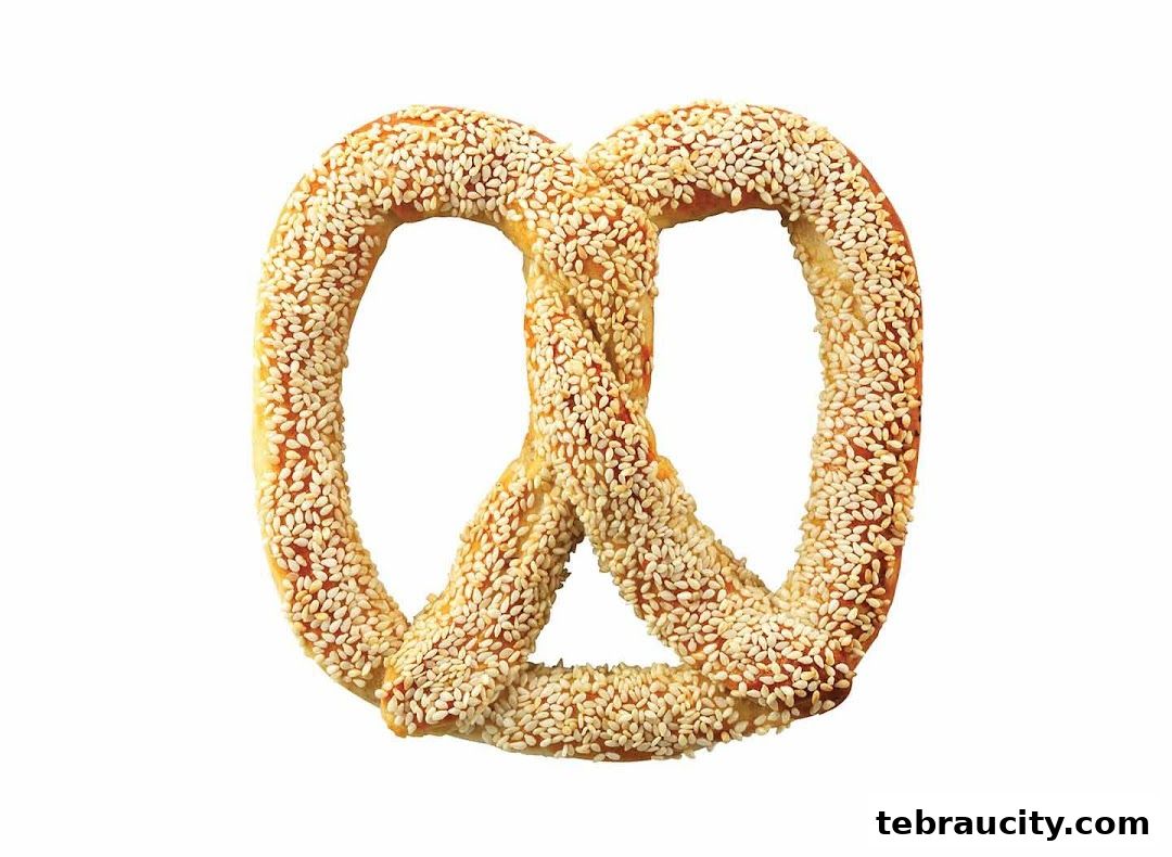 A close-up shot of a sesame seed-covered pretzel on a white background.