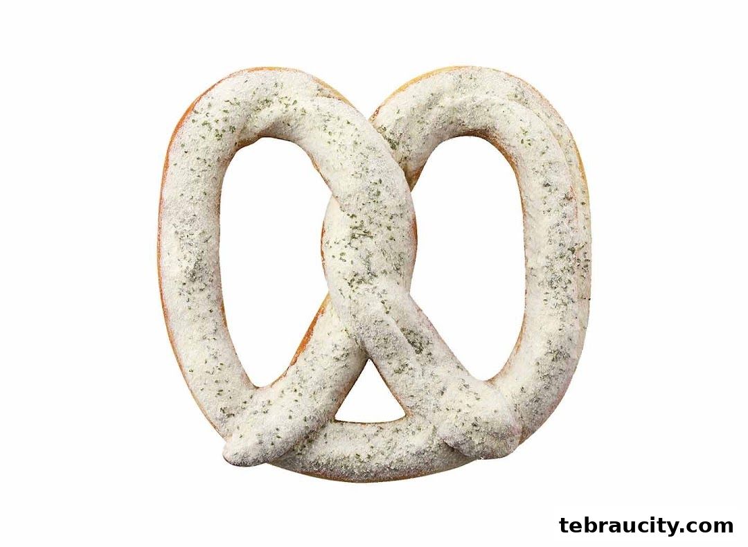 A close-up shot of a pretzel covered in white seasoning and green herbs.
