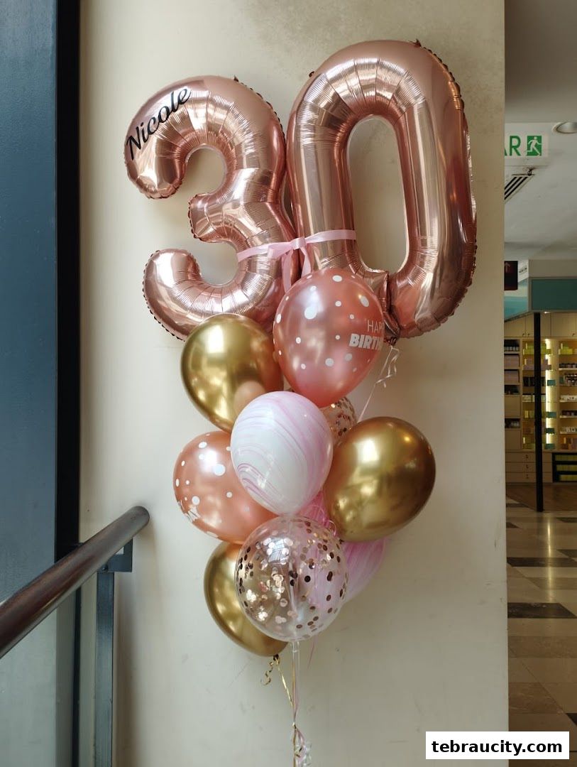 A bouquet of rose gold and gold balloons, including number balloons and a personalized balloon.