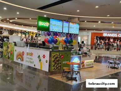A Boost Juice shop with colorful balloons and digital menus displaying various drinks.