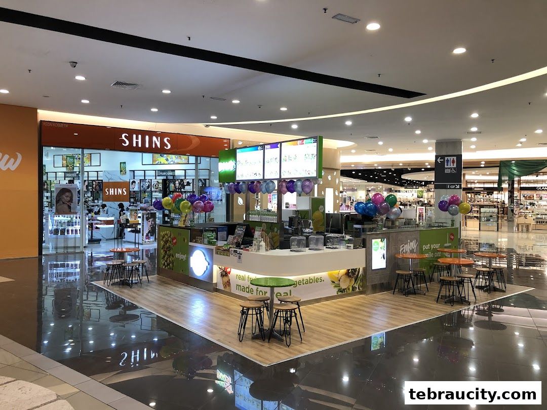 A Boost Juice kiosk with colorful balloons and seating areas in a shopping mall.