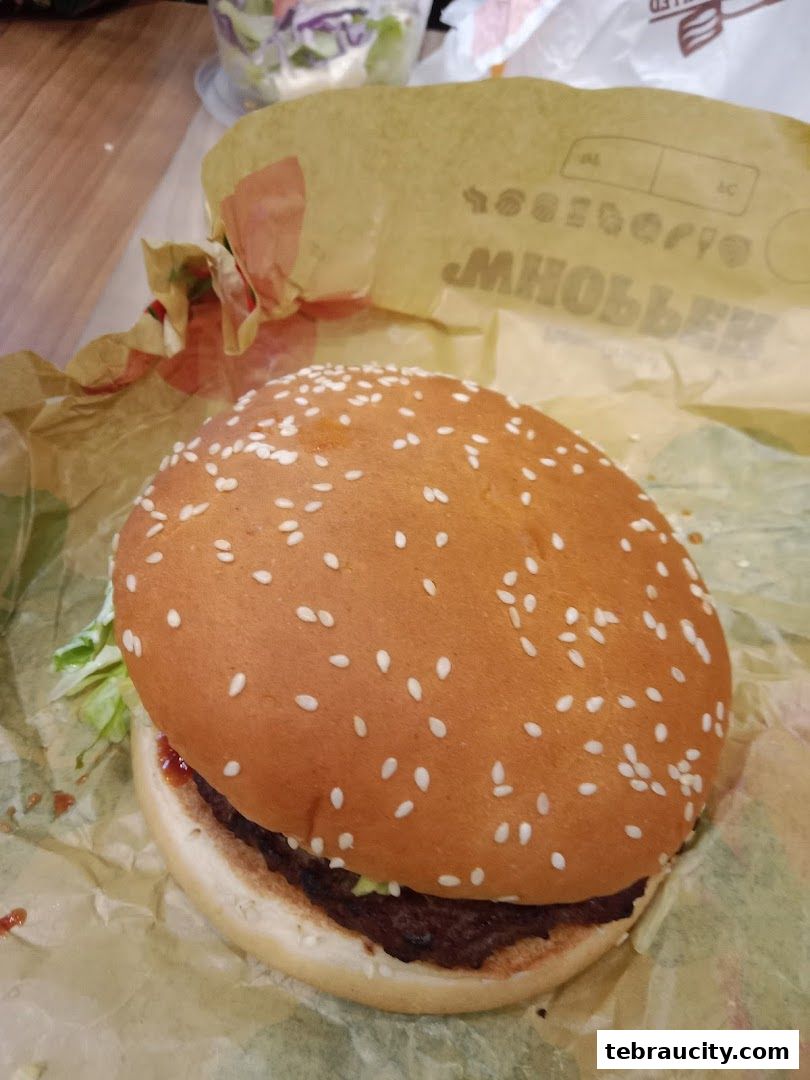 A close-up shot of a sesame seed bun burger from Burger King, with lettuce and sauce visible.