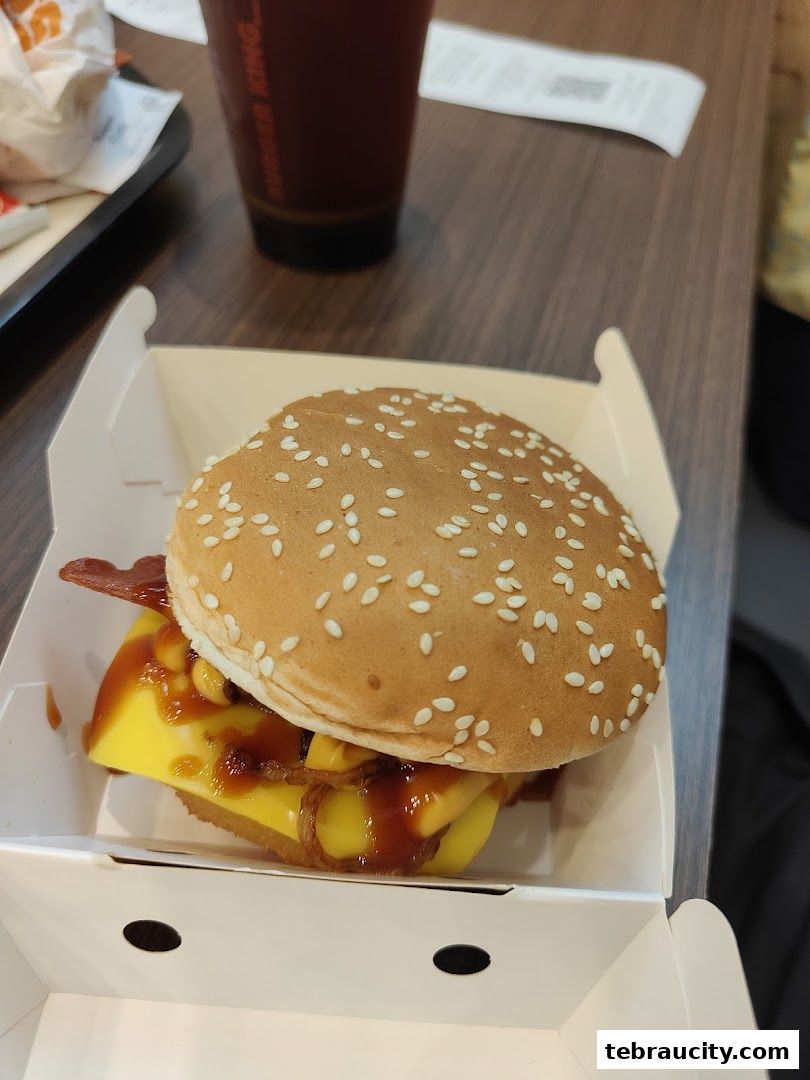 A close-up of a delicious Burger King burger with cheese and bacon in a white box.