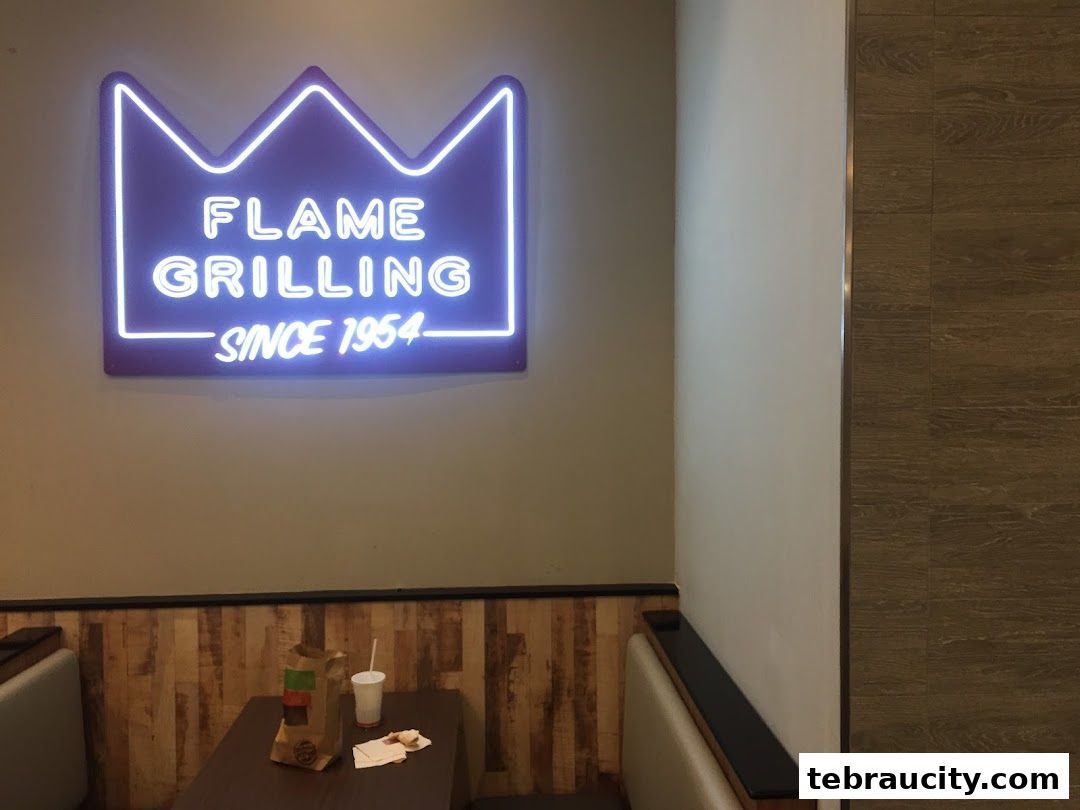 Burger King interior with a neon sign and a table with food packaging.