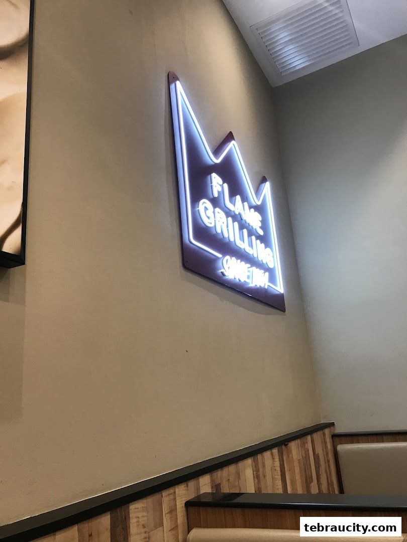 A neon sign that says 'Flame Grilling Since 1954' in a Burger King restaurant.
