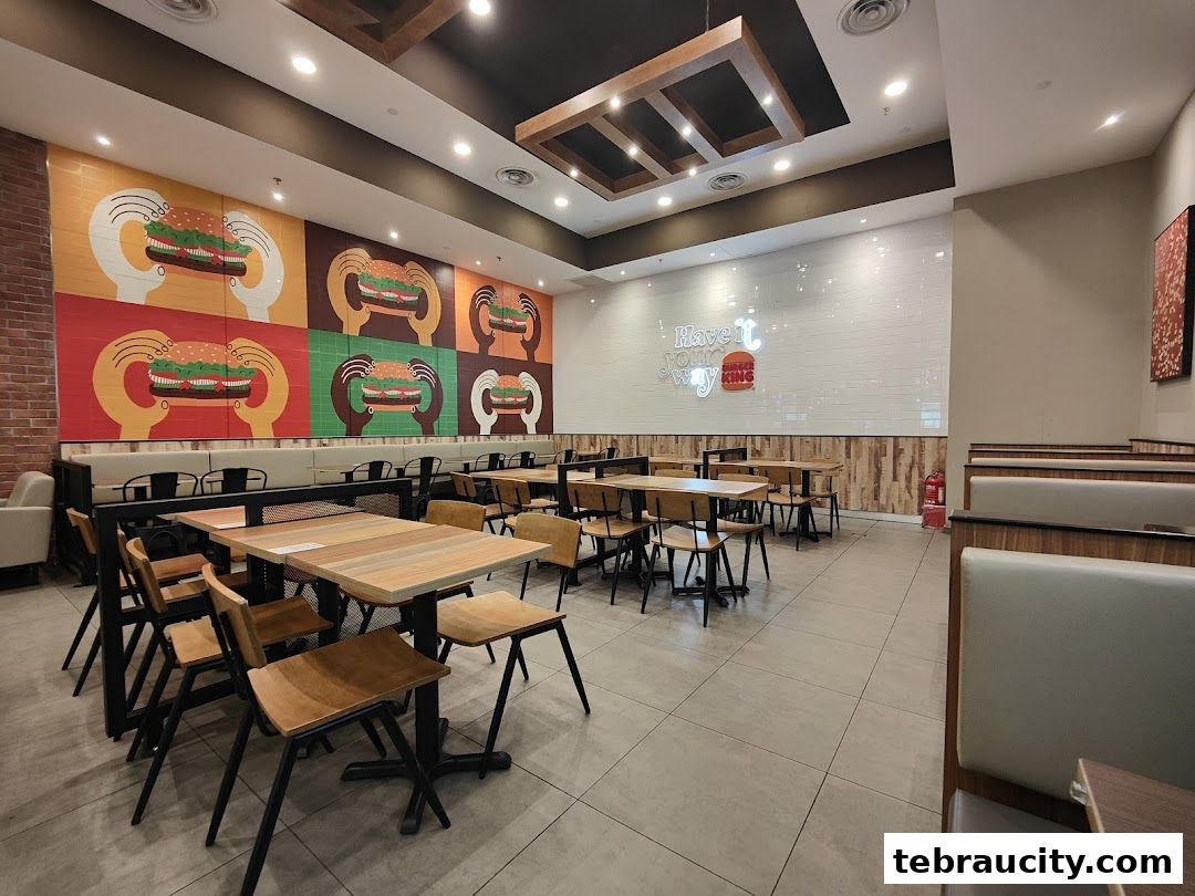 Interior of a Burger King restaurant with seating, tables, and colorful burger artwork on the wall.
