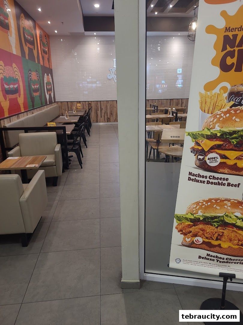 Interior of a Burger King restaurant with seating and promotional posters visible.