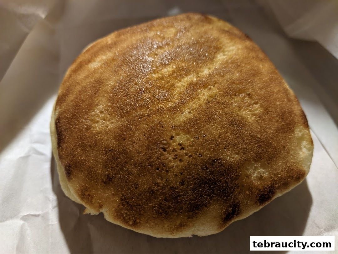 A close-up shot of a golden-brown, fluffy pancake, lightly dusted with sugar.