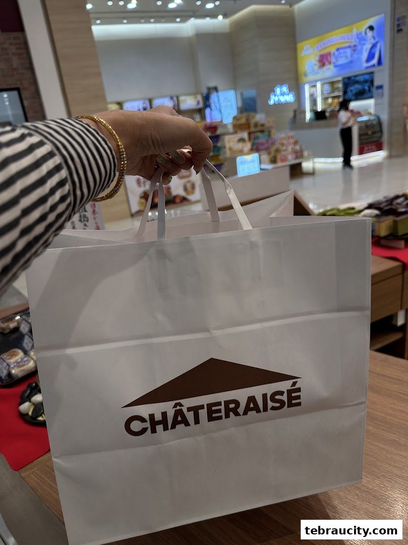 A hand holds a Châteraisé shopping bag in front of the store.