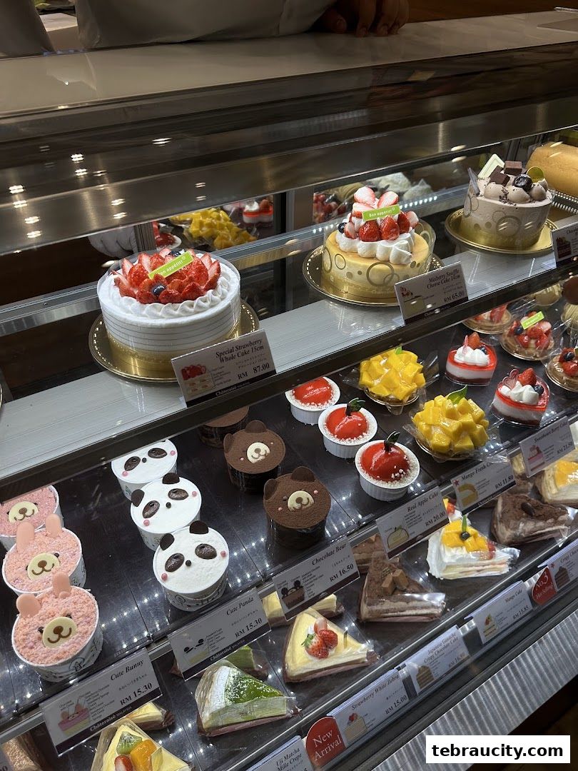 A display case filled with various beautifully decorated cakes and desserts, including strawberry cakes and cute animal-themed treats.